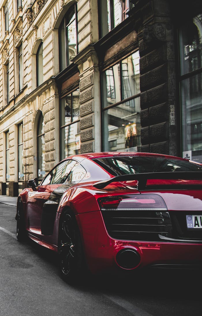 our-services-3 Sleek red sports car parked on a charming historic street in Prague, highlighting urban elegance and powerful design.